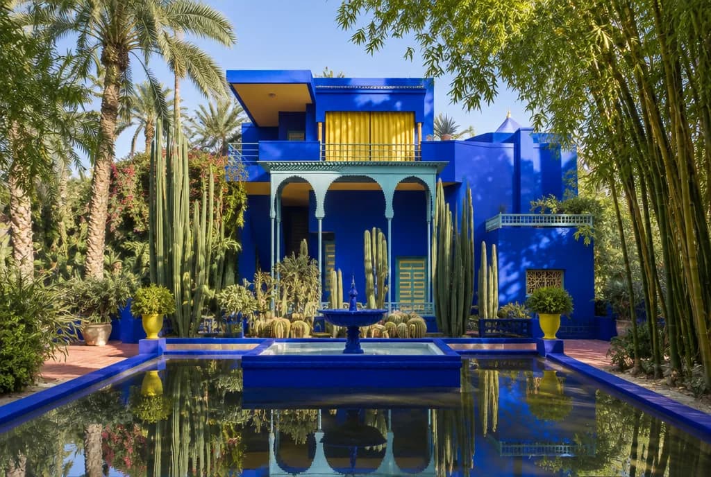Den koboltblå villaen i Jardin Majorelle og bassenget, innrammet av kaktuser, palmer og bambus